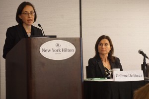woman standing behind podium with a seated panelist watching speaking about the refugee crisis during the European Law section at the 2016 Annual Meeting